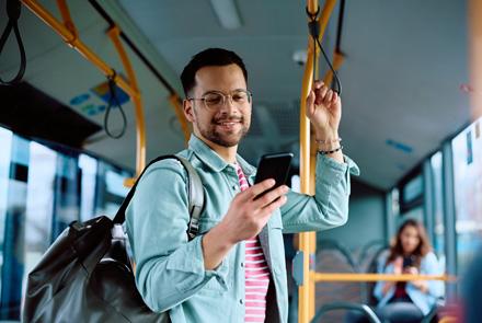 persona in piedi sull'autobus che utilizza l'app sul suo smartphone